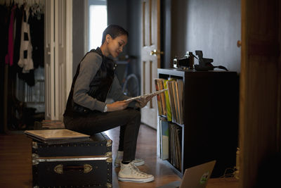 Side view of young woman using mobile phone at home