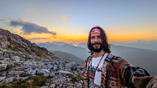 Portrait of young woman standing against sky during sunset