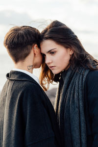 Lesbian women embracing while standing against sea