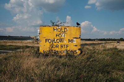 Information sign on field against sky