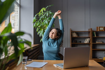 Happy business woman stretching at workplace, female employee resting from computer screen