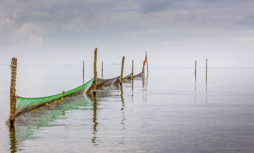 Wooden post in sea against sky