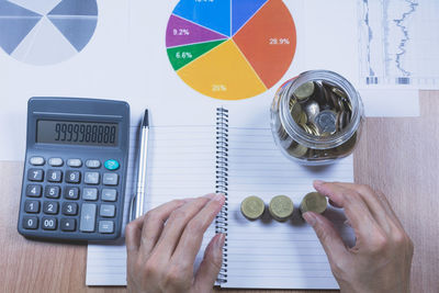 Cropped hands of businesswoman stacking coins on desk in office