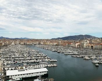 High angle view of boats at marina against cloudy sky