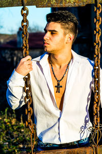 Man standing against rusty swing in sunny day