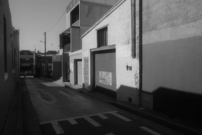 Empty road by buildings against sky in city