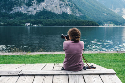 Rear view of woman photographing lake