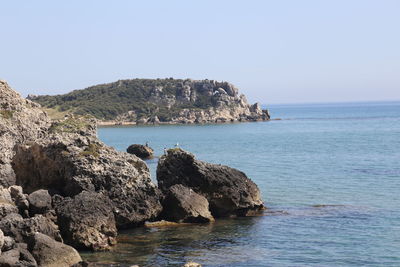 Scenic view of rocks in sea against clear sky