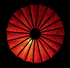 Low angle view of red umbrella against black background