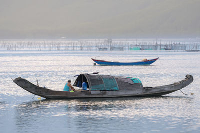 Side view of man in boat on sea against sky