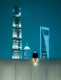 Rear view of woman standing against modern buildings