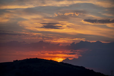 Scenic view of silhouette mountains against orange sky