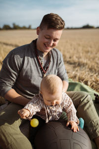 Father with baby sitting on man