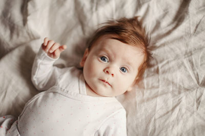 High angle portrait of cute baby girl lying on bed