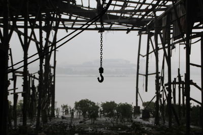 Hook hanging in abandoned building against lake