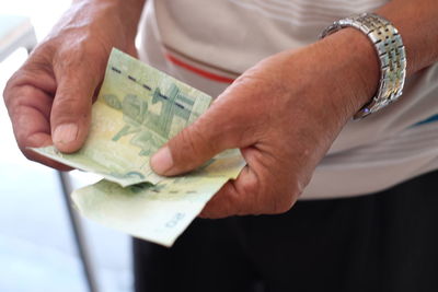 Midsection of man holding paper currencies