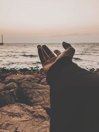 Man relaxing on beach against sky during sunset