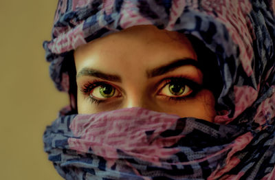 Close-up portrait of young woman covering face with scarf