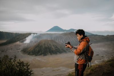 Side view of man photographing against mountains