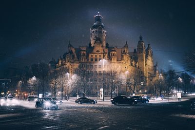 Cars on illuminated city against sky at night