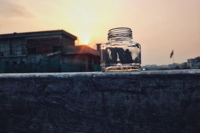 Close-up of old building against sky during sunset with a glass bottle