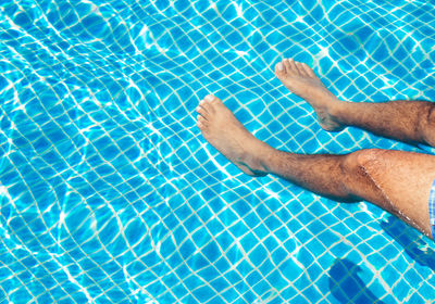 Low section of man relaxing on swimming pool
