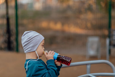 Portrait of cute boy with down syndrome enjoying tea at park, copy space