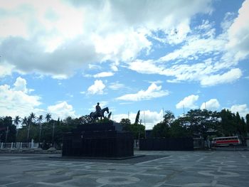 Statue in city against cloudy sky