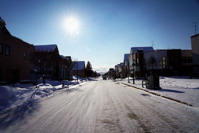 Road amidst snow covered buildings against sky