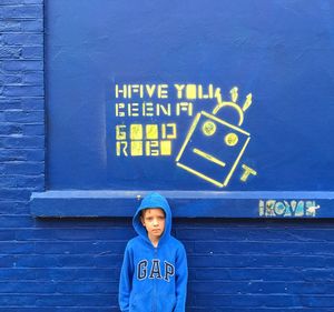 Portrait of boy standing against blue wall