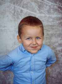 Portrait of cute boy standing against wall