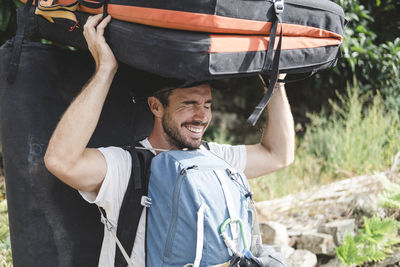 Portrait of a rock climber carrying crashpad and backpacks