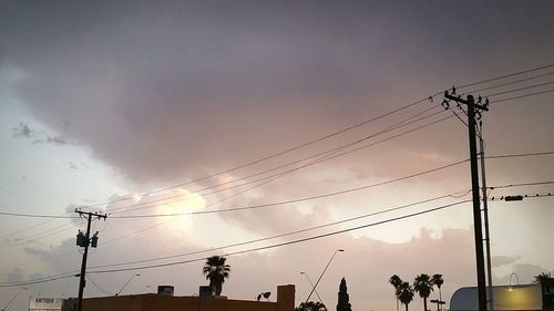 Low angle view of silhouette electricity pylon against sky