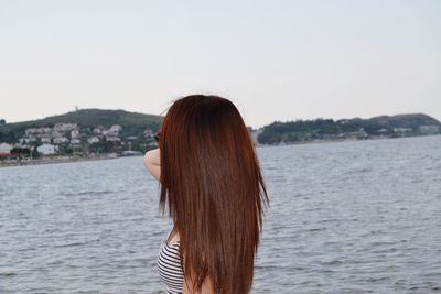 Woman standing by sea against sky