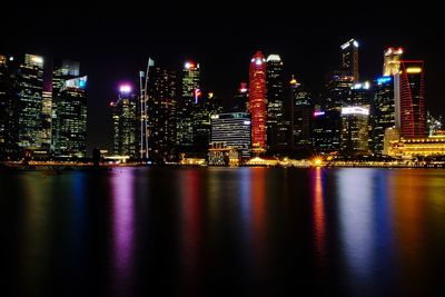 Illuminated buildings by river at night