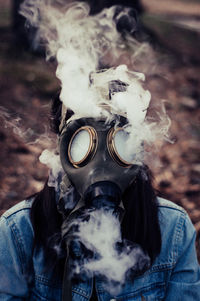 Close-up of woman wearing gas mask with smoke