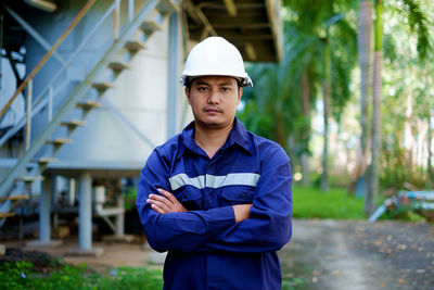 Portrait of confident engineer with arms crossed against workshop