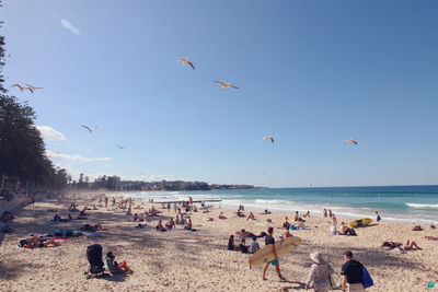 People at beach against clear sky