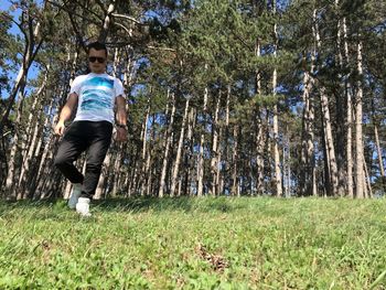 Full length of young man amidst trees in forest