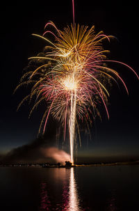 Low angle view of firework display over river at night