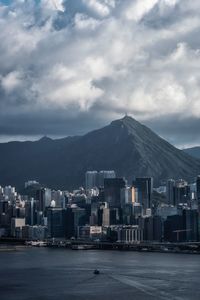 Buildings at waterfront against cloudy sky