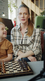 Portrait of mother and daughter playing chess at home