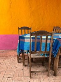 Empty chairs and table against yellow wall