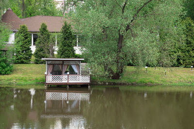 House by lake against trees and plants