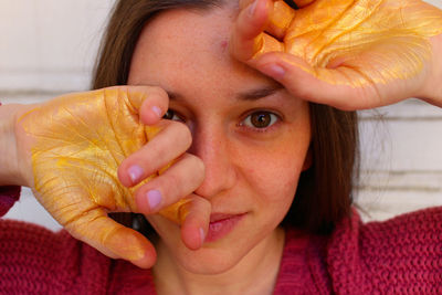 Close-up portrait of woman with painted hands