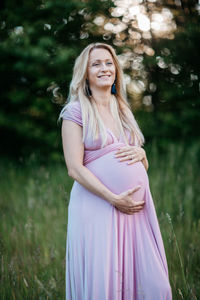 Happy pregnant woman standing on field