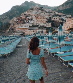 Rear view of woman on shore against city