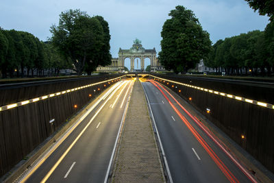 Light trails on roads against triumphal arch