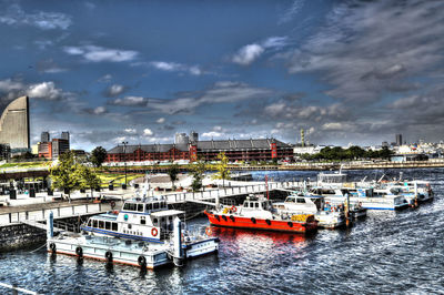 Boats moored on river in city against sky