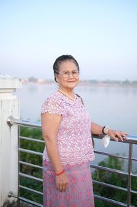 Portrait of young woman standing against lake